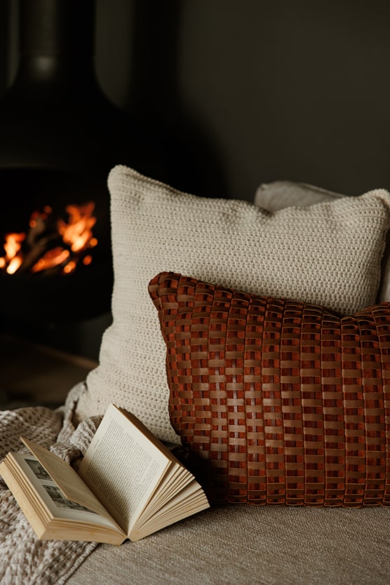 Handwoven Tressera Cushion placed on couch in cozy setting with fireplace